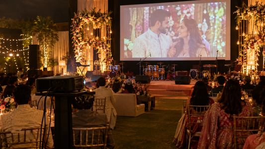 Projected couple video on a large screen at an Indian wedding sangeet with guests seated