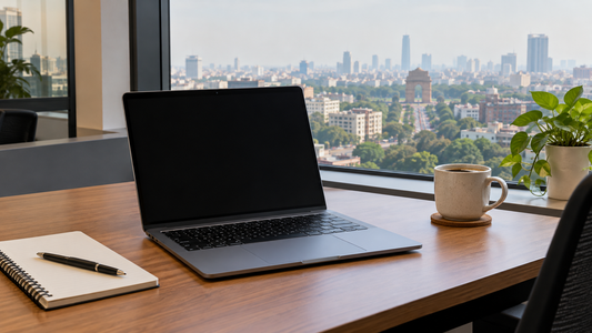 Open laptop on a desk by a window with the Delhi skyline and India Gate in the distance