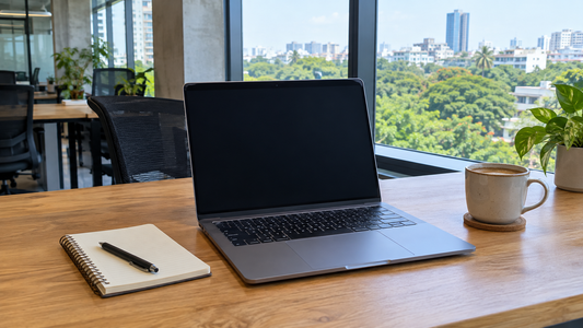 Open laptop on a desk in a Bengaluru startup office with green trees visible through large windows